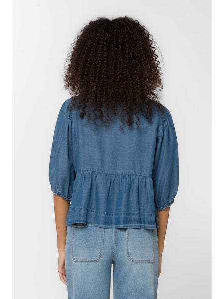 Person wearing a denim top and jeans against a white background