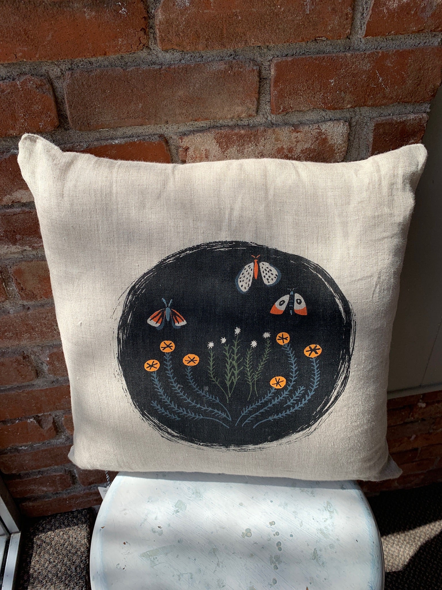 Black circle with moth and flower print. Colors include black, orange, and navy blue.