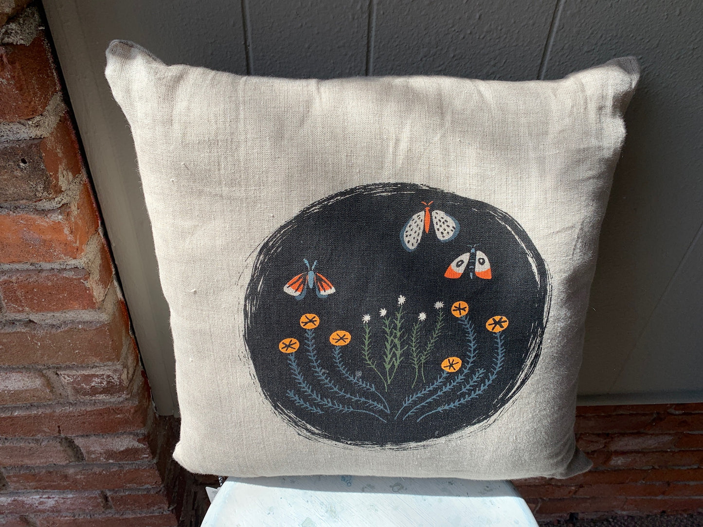 Black circle with moth and flower print. Colors include black, orange, and navy blue.