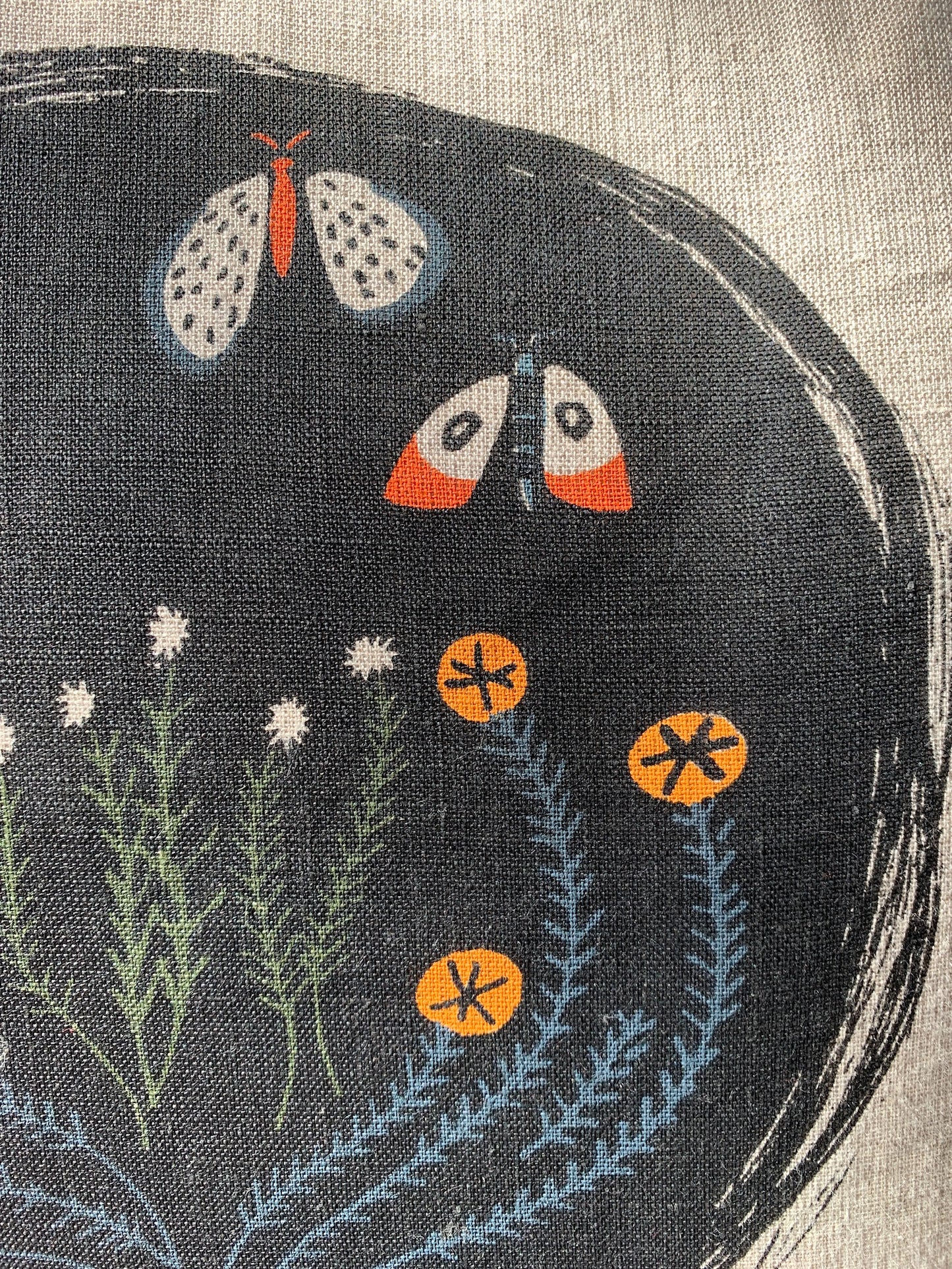 Black circle with moth and flower print. Colors include black, orange, and navy blue.