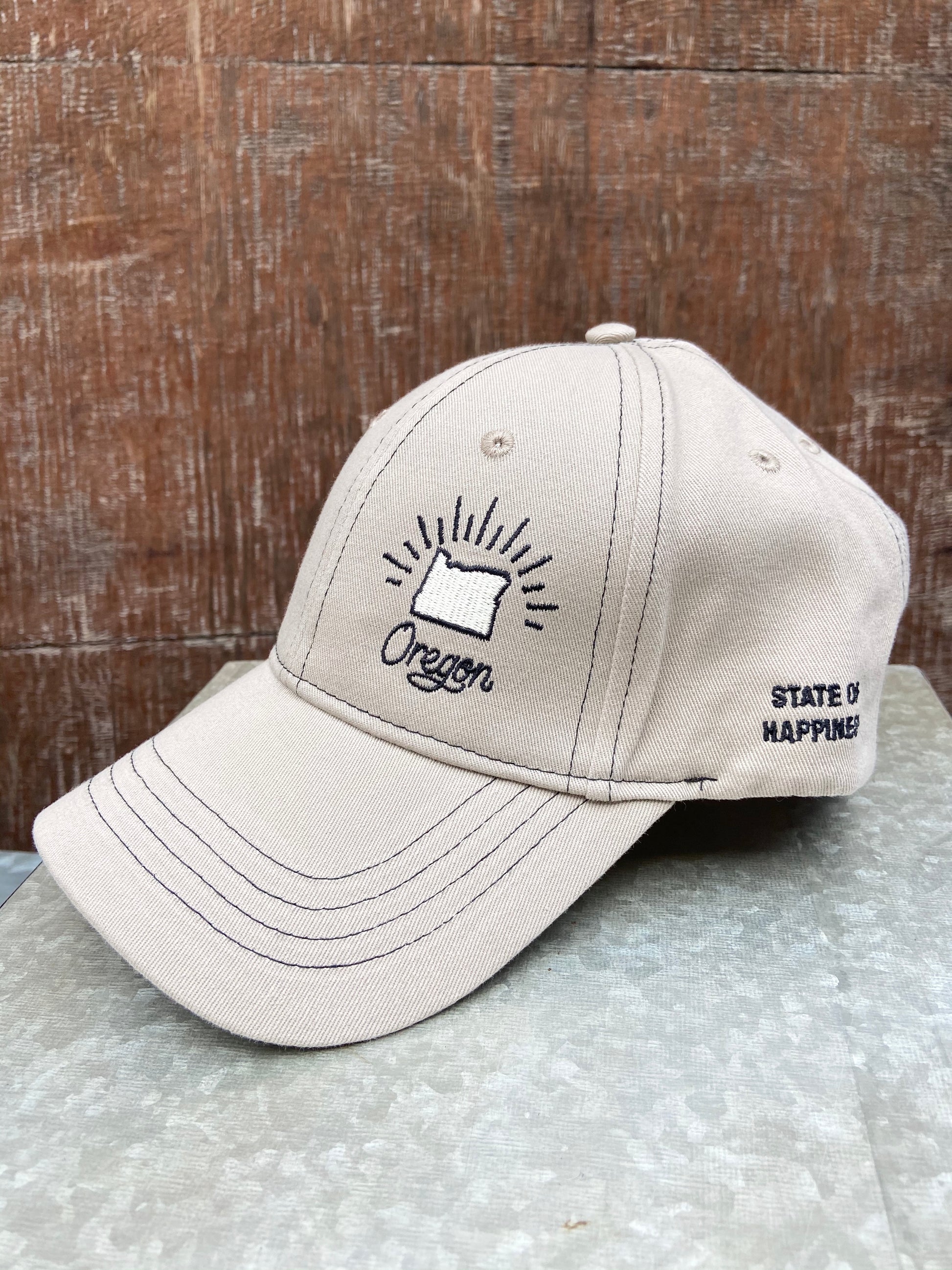 Tan ball cap with black stitching. Adjustable back with slide buckle.